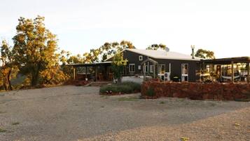 A modern house with a covered porch, a stone wall, and a gravel driveway.