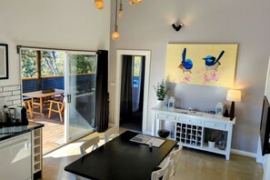 A modern kitchen with a dining area, a sliding glass door leading to an outdoor space, and a wall-mounted artwork of birds.