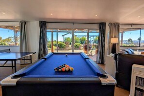 A pool table with balls in the center, a ping pong table to the left, and a sofa with a bookshelf to the right. - Abercrombie Ridge - Lux LODGE and Spa Retreat (Curraweela)