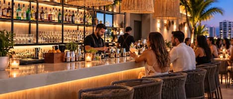 Un espace bar avec des chaises en osier, un comptoir et des étagères remplies de bouteilles et de verres.