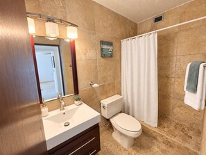 Un bagno con lavandino, WC e tenda per la doccia.