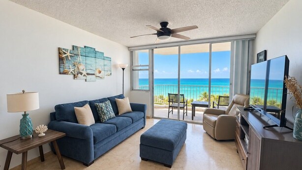A living room with a blue sofa, a coffee table, a TV, and a view of the ocean. - Beachfront in * Isla Verde * walk 2 eat * (Carolina)