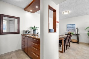A modern kitchen with a built-in oven, a sink, and a dining area with a table and chairs.