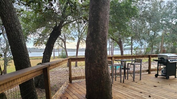 A wooden deck with a metal railing, a grill, and outdoor seating.