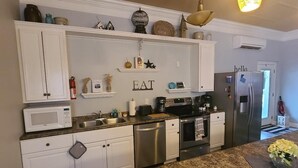 A modern kitchen with white cabinetry, stainless steel appliances, and decorative items on shelves.