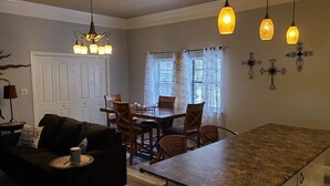 A modern kitchen with a granite countertop, a dining area with a table and chairs, and a living room with a sofa and a coffee table.