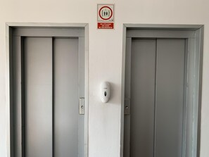 Kaksi suljettua ovea, joiden yläpuolella on kyltti, jossa lukee, että niitä ei saa käyttää hätätilanteissa, ja niiden väliin seinään on asennettu ovitunnistin.