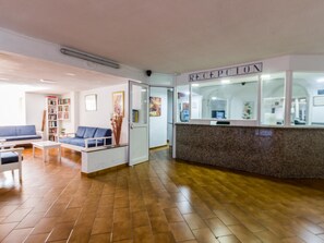 Un espace d’accueil comprenant un comptoir de réception, un canapé bleu et une bibliothèque.