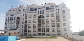 Een meerlaags woongebouw met balkons, een zwembad en een reddingsboei.
