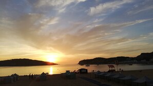 Ein Strand bei Sonnenuntergang mit Zelten und einem Rettungsring.
