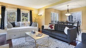 A living room with a sofa, a coffee table, and a dining area with a table and chairs.