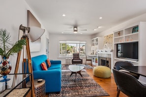 Relax in this spacious living area with a large window offering a view of the outdoors, a comfortable sofa, and a variety of seating options.