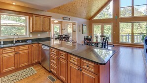 A spacious kitchen with wooden cabinets, a large island, and a view of the outdoors through large windows. - Lakehouse with covered dock, slide, and outdoor kitchen! Close to I-75, trails. (Caryville)