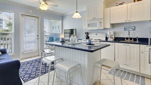Una cocina con gabinetes blancos, encimera azul y ventilador de techo.