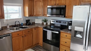 A modern kitchen with wooden cabinets, stainless steel appliances, a dishwasher, and a coffee maker. - Douglas Lake, TN Lake View Retreat with lake access (Newport)