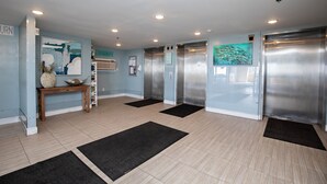 A modern elevator area with a wooden console table, black mats, and stainless steel elevators. - OPEN 10/3-10/5 OR 10/19-10/26 2 FREE Beach chairs  Condo on the Beach (Panama City Beach)