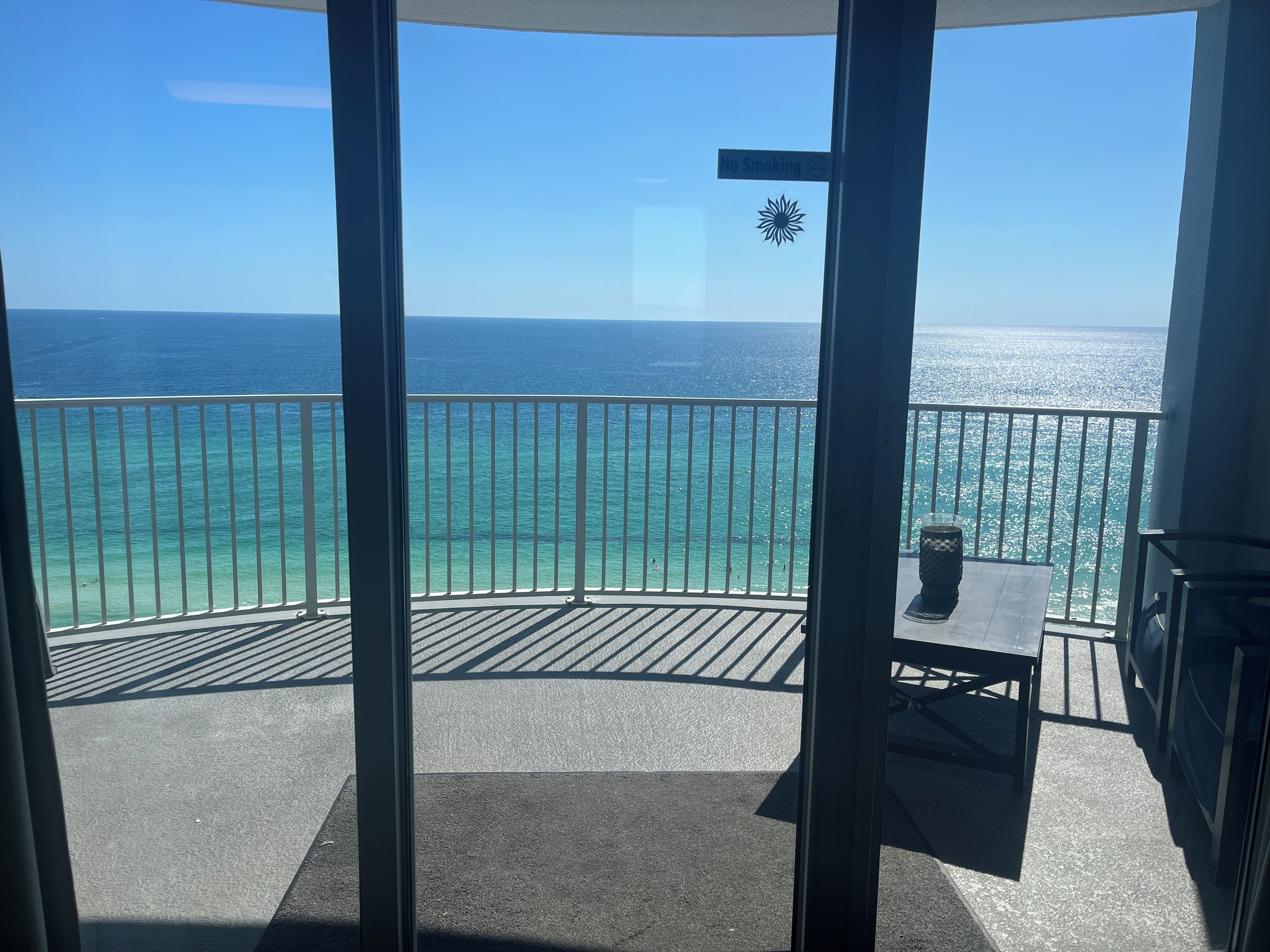A balcony with a view of the ocean, a 'No Smoking' sign, and a sun emblem.