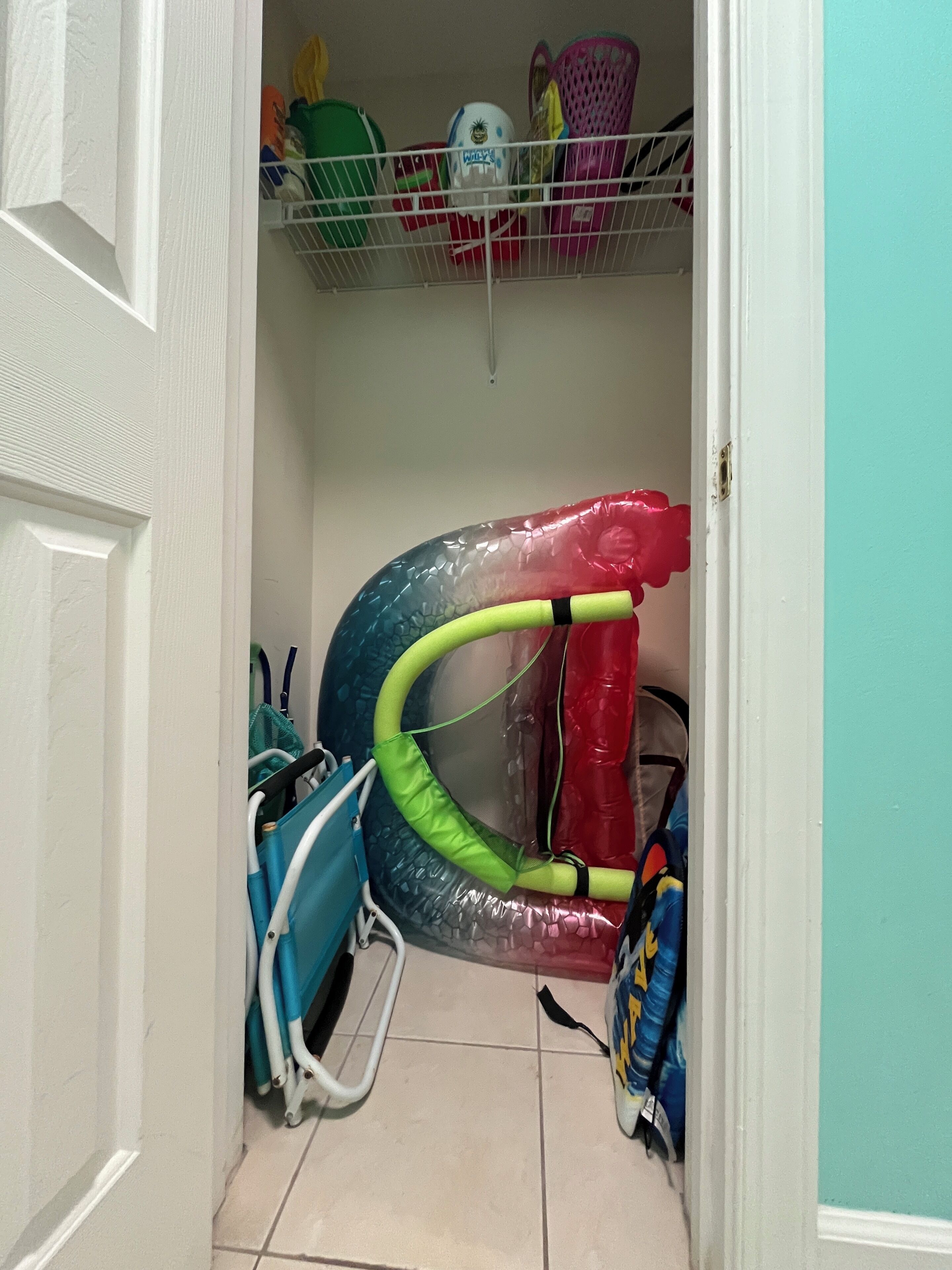 A narrow hallway with a door on the left, a blue chair on the right, and a colorful inflatable structure in the center.