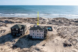 A beachfront property with two multi-story buildings, a swimming pool, and a sandy beach area.