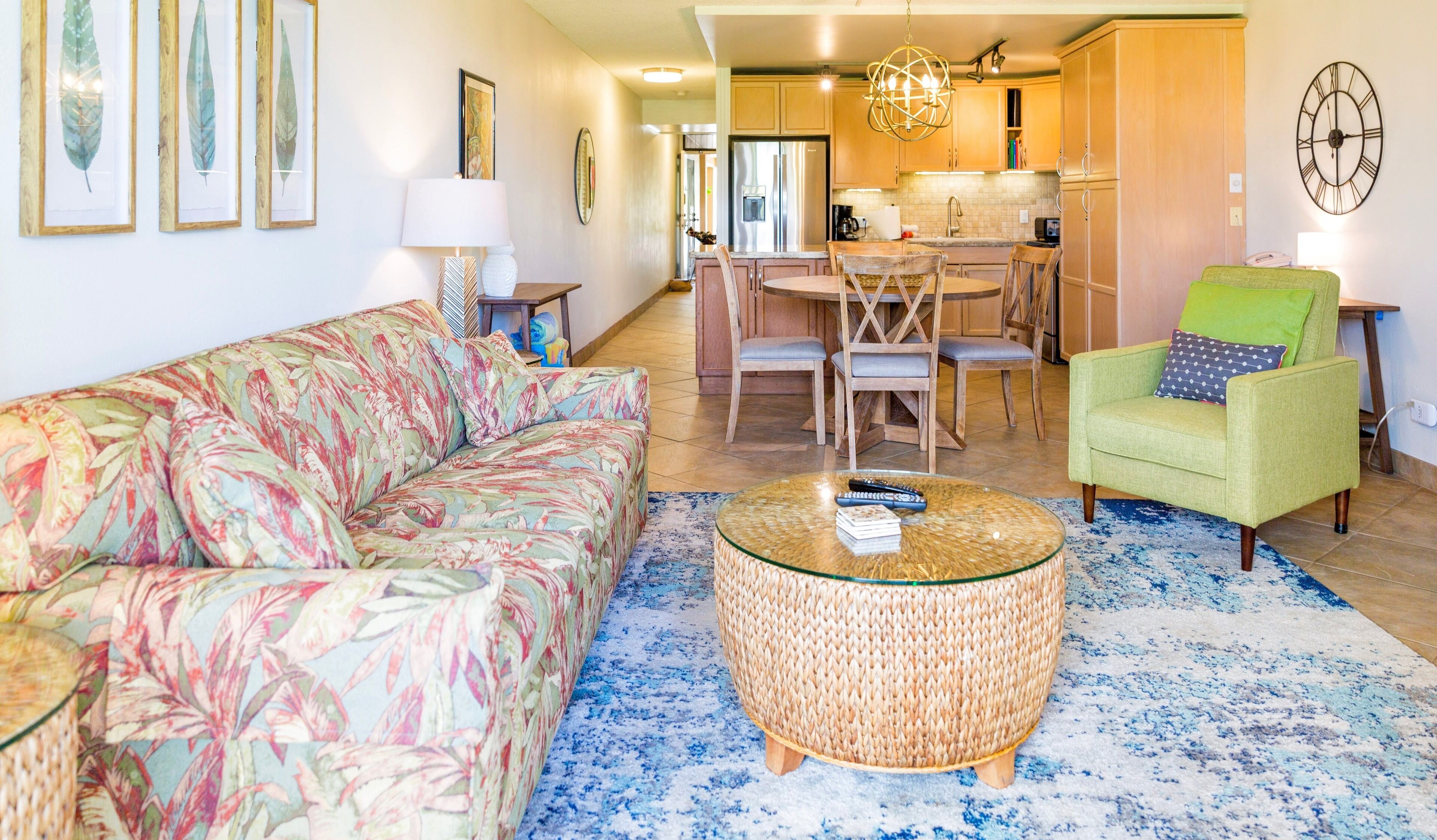 A living room with a sofa, a green armchair, a round coffee table, and a dining area with chairs and a table.