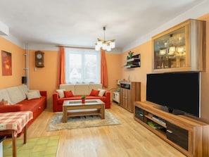 Uma sala de estar com sofá, mesa de centro, televisão e um armário.