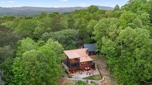 Une cabane entourée d’une forêt dense, dotée d’une terrasse et d’un espace salon extérieur.