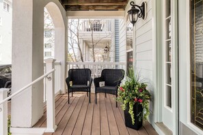 A covered porch with two wicker chairs and a potted plant. - Sunset Island 12 Shore Point Drive (Ocean City)