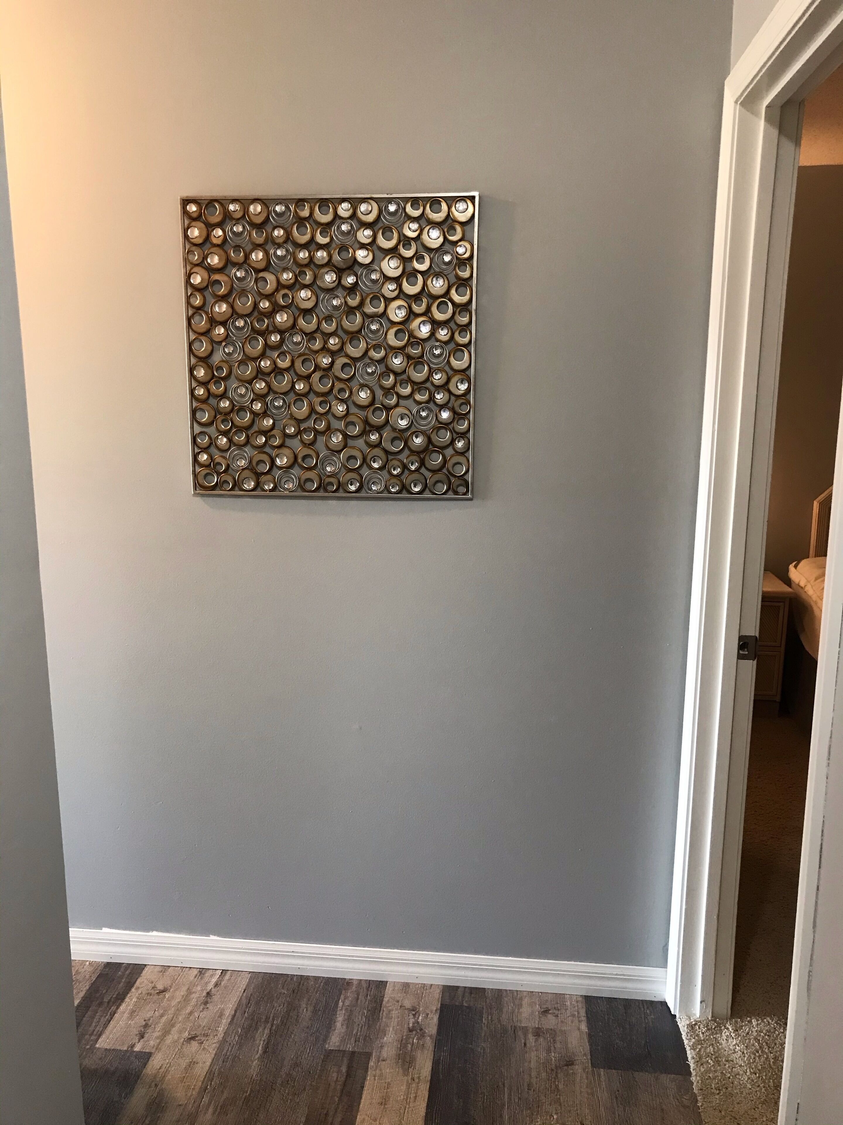 Un pasillo con pared gris y un panel metálico decorativo.