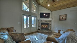 A cozy living room with leather sofas, a fireplace, and a TV mounted above it. - Serenity Now - Cherry Log (Cherry Log)