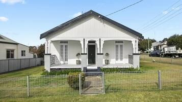 A single-story house with a front porch, a small front yard, and a metal fence.