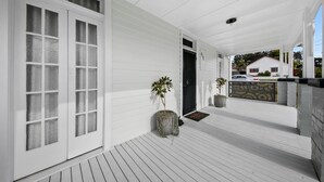 A white exterior with a covered porch, a door with frosted glass panels, and potted plants. - Pollyanna Hunter Valley (Cessnock)