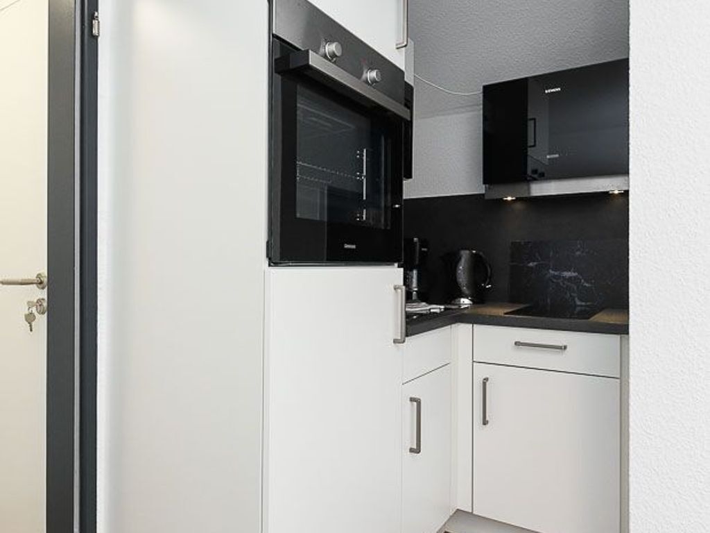 Una cocina compacta con horno integrado, cafetera y microondas.