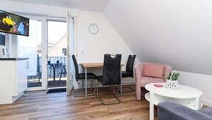 A modern living space with a dining area, a sofa, and a TV. - Vacation apartment Abendstern (5) - Holiday apartments in Haus Seekieker in Bensersiel (Esens)