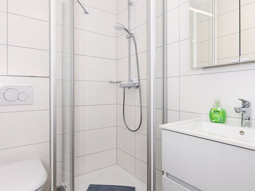 Un baño moderno con cabina de ducha de vidrio, un lavabo blanco y un espejo sobre el lavabo.