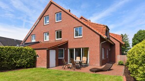 A two-story brick house with a patio, a sliding glass door, and a small outdoor seating area.