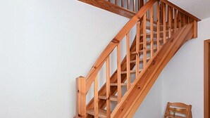 Een houten trap met een leuning en een stoel aan de onderkant.