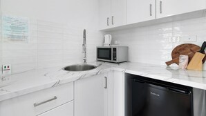 A modern kitchen with white cabinets, a stainless steel sink, a microwave, and a dishwasher.