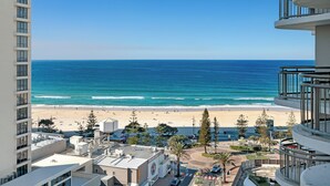 A beachfront hotel with a view of the ocean, a sandy beach, and a parking area.