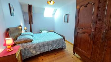 A bedroom with a bed, a wardrobe, a nightstand, a lamp, and a ceiling light fixture.