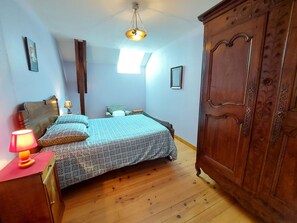 Une chambre à coucher comprenant un lit, une armoire, une table de chevet, une lampe et un luminaire au plafond.