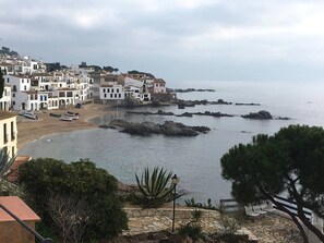 A coastal town with white buildings, a beach, and rocky outcrops in the water.