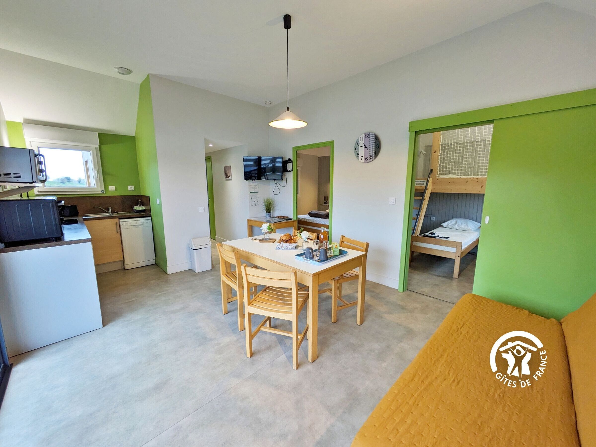 Um espaço compacto com cozinha compacta, área de refeições e uma cama beliche.