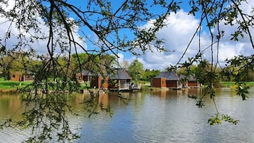 A lakeside view with several wooden cabins and a grassy area.