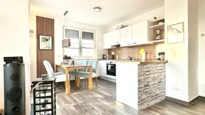 A modern kitchen with a central island, wooden flooring, and a dining area with a table and chairs. - Apartment sun deck - Haffresidenz (4a.12) - 4a.12 (Zirchow)