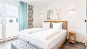 A modern bedroom with a large bed, a small bedside table, and a view of the outside. - Apartment sun deck - Haffresidenz (4a.12) - 4a.12 (Zirchow)