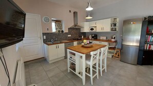 A modern kitchen with white cabinets, a wooden island, a built-in microwave, and a stainless steel refrigerator. - Riverside Retreat: Spacious 3BR House, Private Fishing Pond, Near Charming Villages & Outdoor Activities (Voutré)
