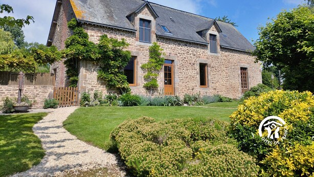 A stone house with a sloped roof, a wooden door, and a gravel path leading to the entrance.