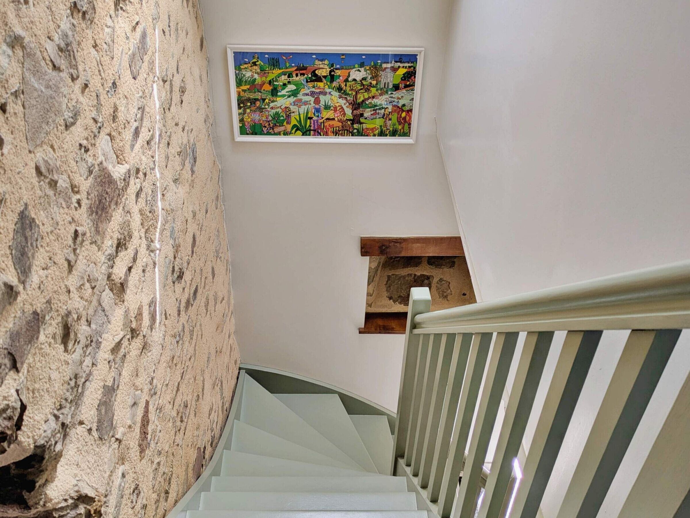 Una escalera con un muro de piedra en un lado y barandilla de madera.