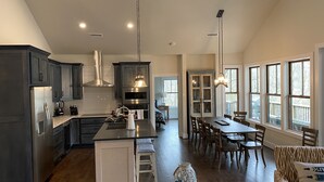A spacious kitchen with dark cabinets, a central island, and pendant lighting.
