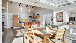 Uma sala de jantar espaçosa com mesa e cadeiras de madeira, uma cozinha com armários de madeira e um claraboia.